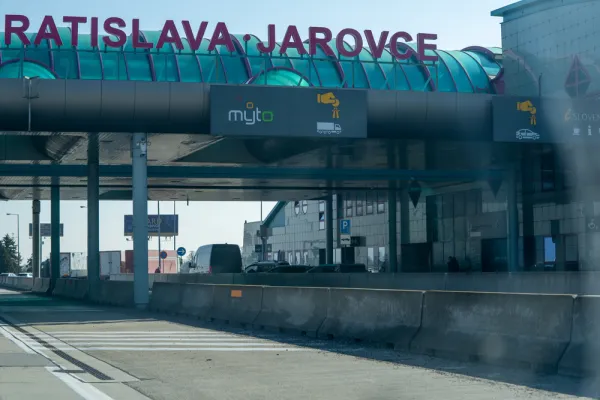 Bratislava-Jarovce border crossing with Myto toll system sign for heavy vehicles, eznamka vignette sales point and i Slovensko information centre visible under teal canopy, February 2026